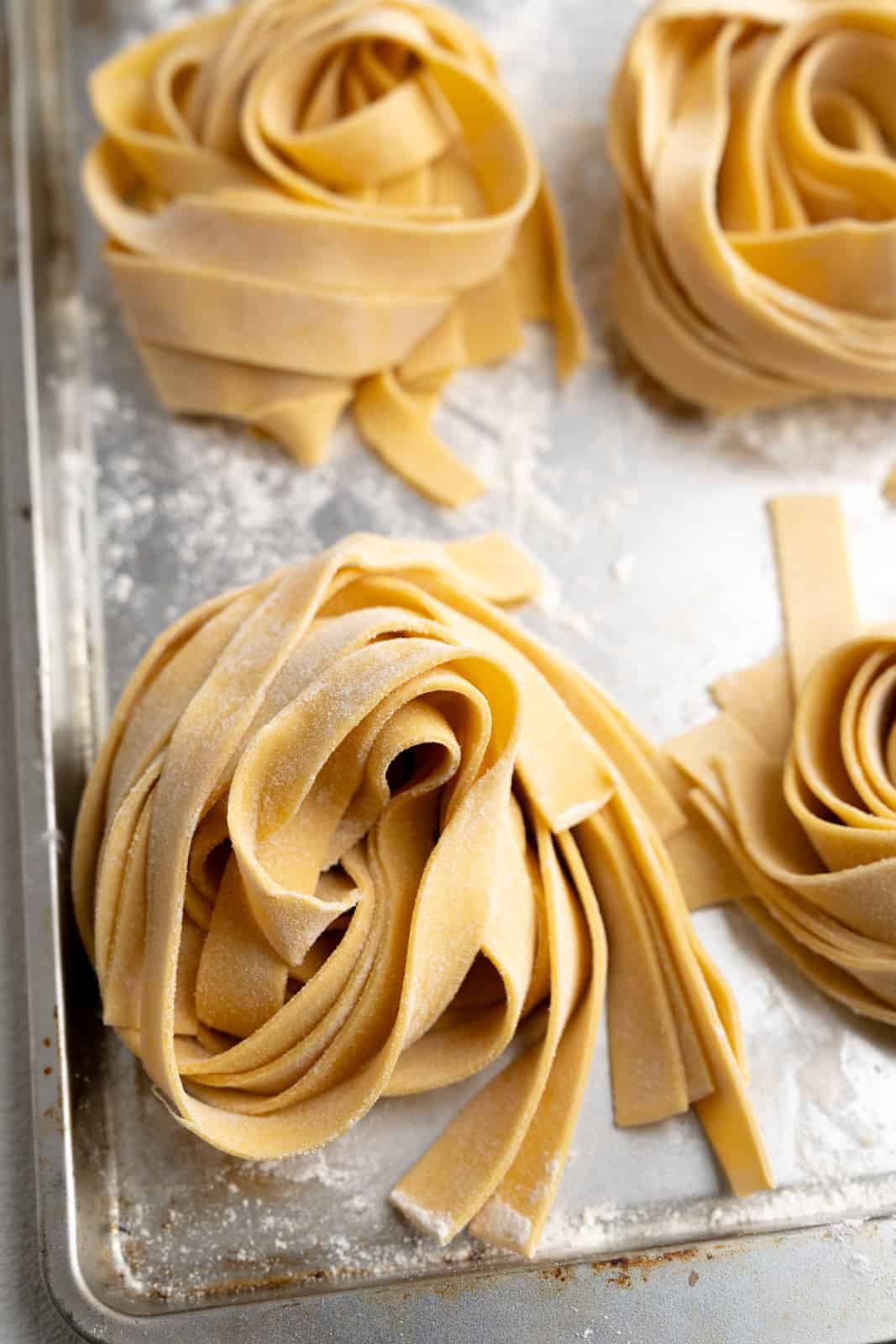 4 fresh homemade pasts pappardelle nests on a baking sheet