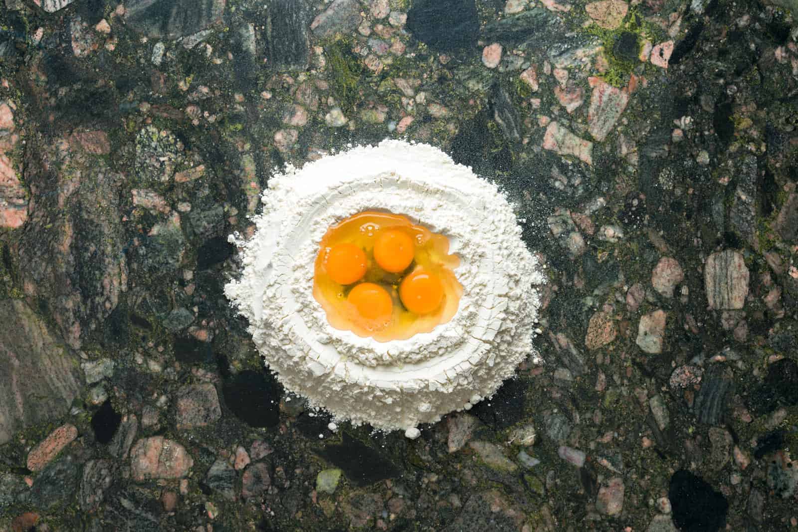 Four eggs inside a flour well in preparation for making fresh pasta