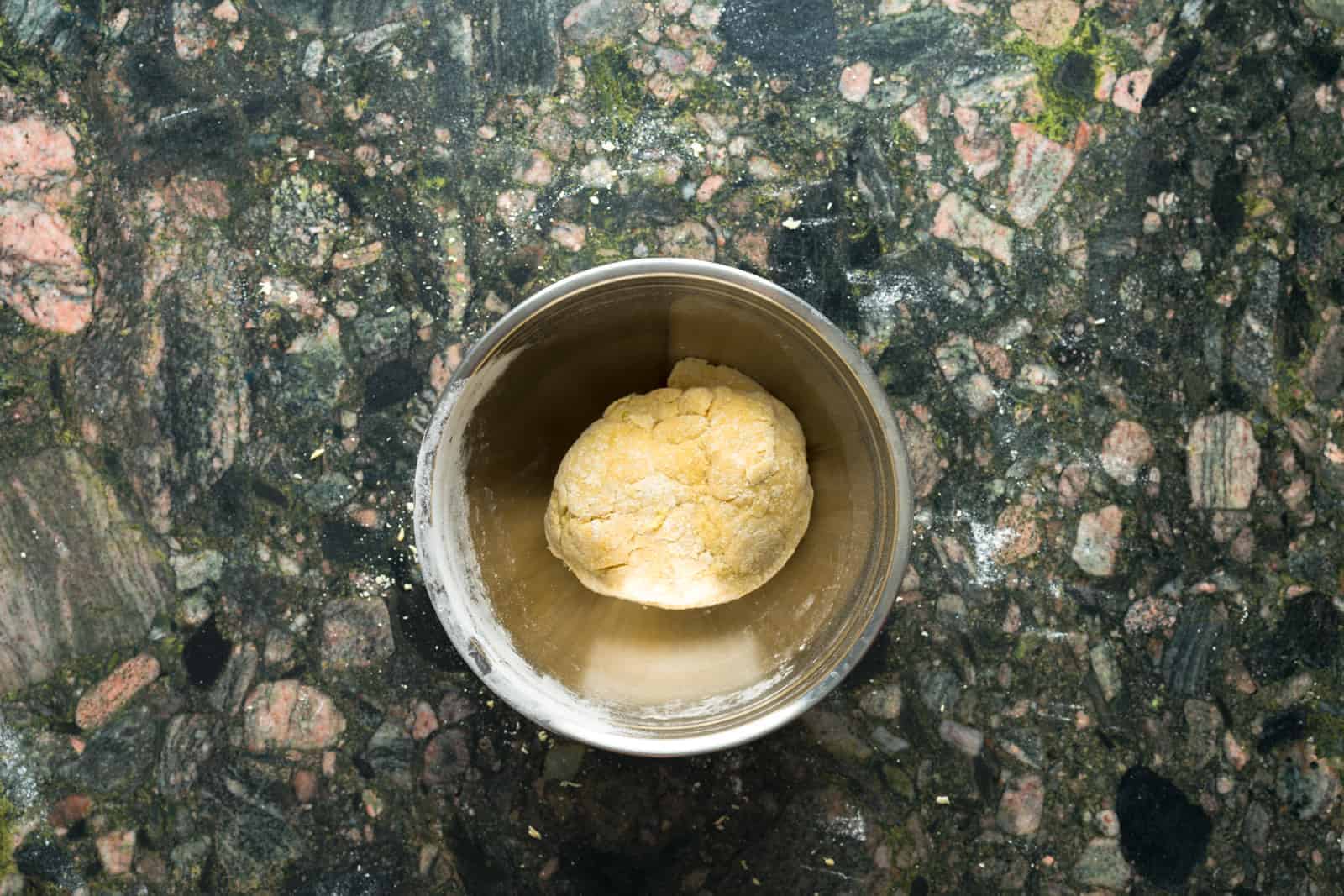 Fresh pasta dough ball resting in a stainless steel bowl