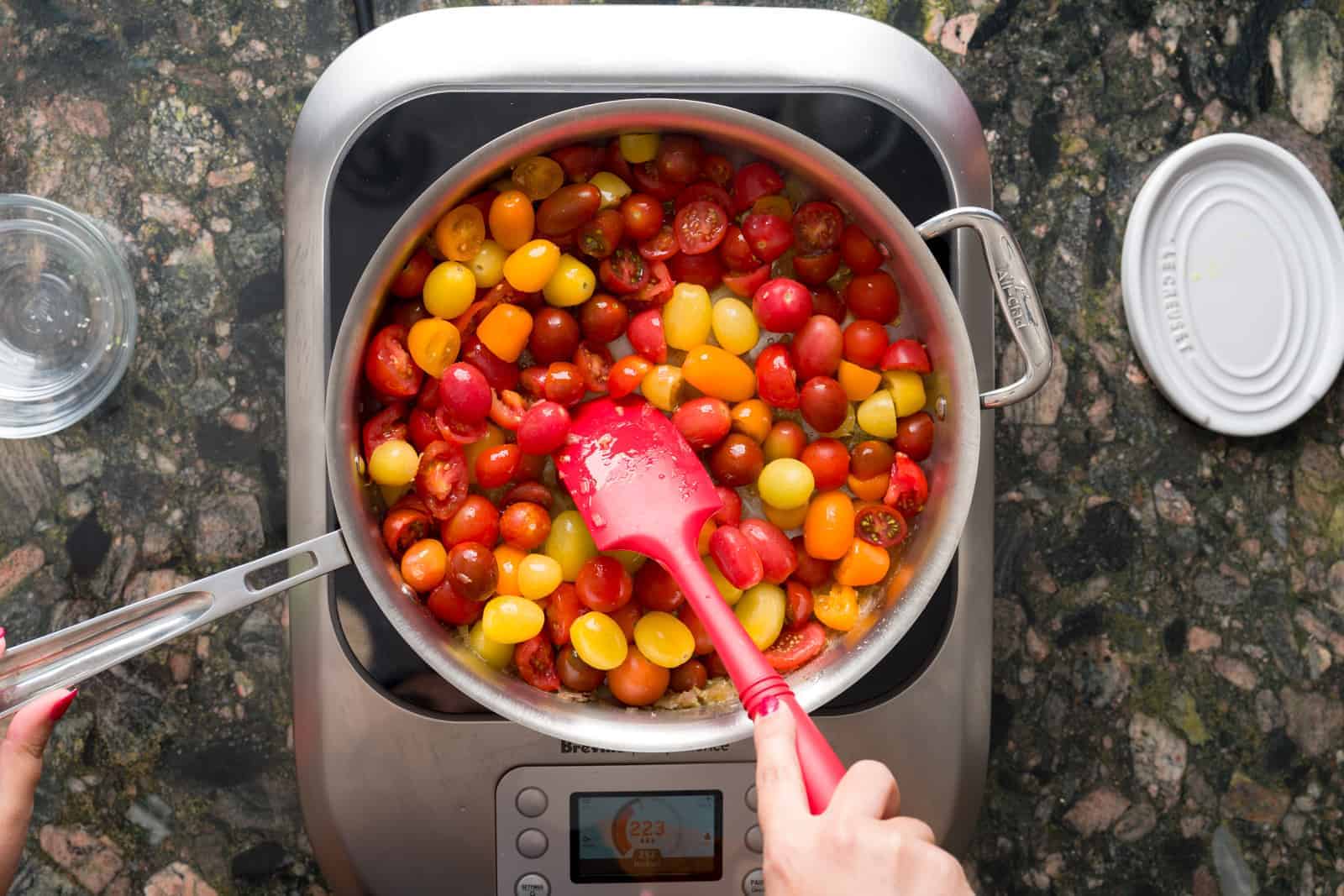 Sautéing cherry tomatoes in the pan with shallots in olive oil and butter.