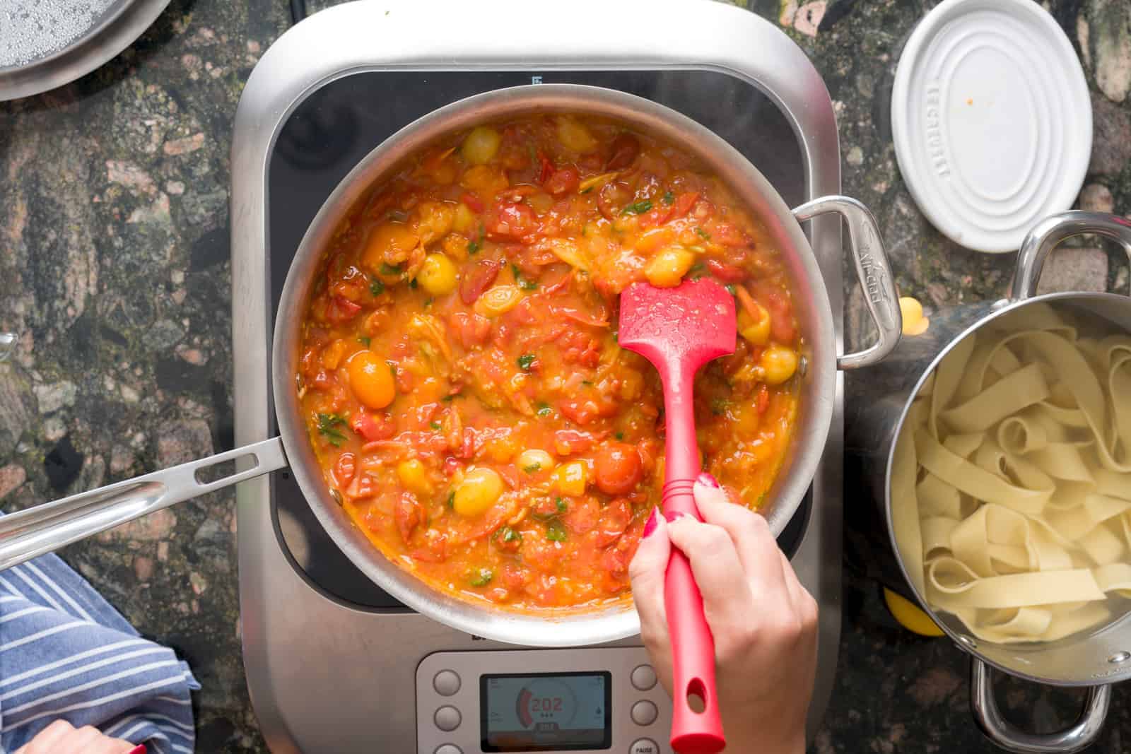 Making fresh tomato sauce - squishing the cherry tomatoes in the pan with basil and shallots in olive oil and butter. 