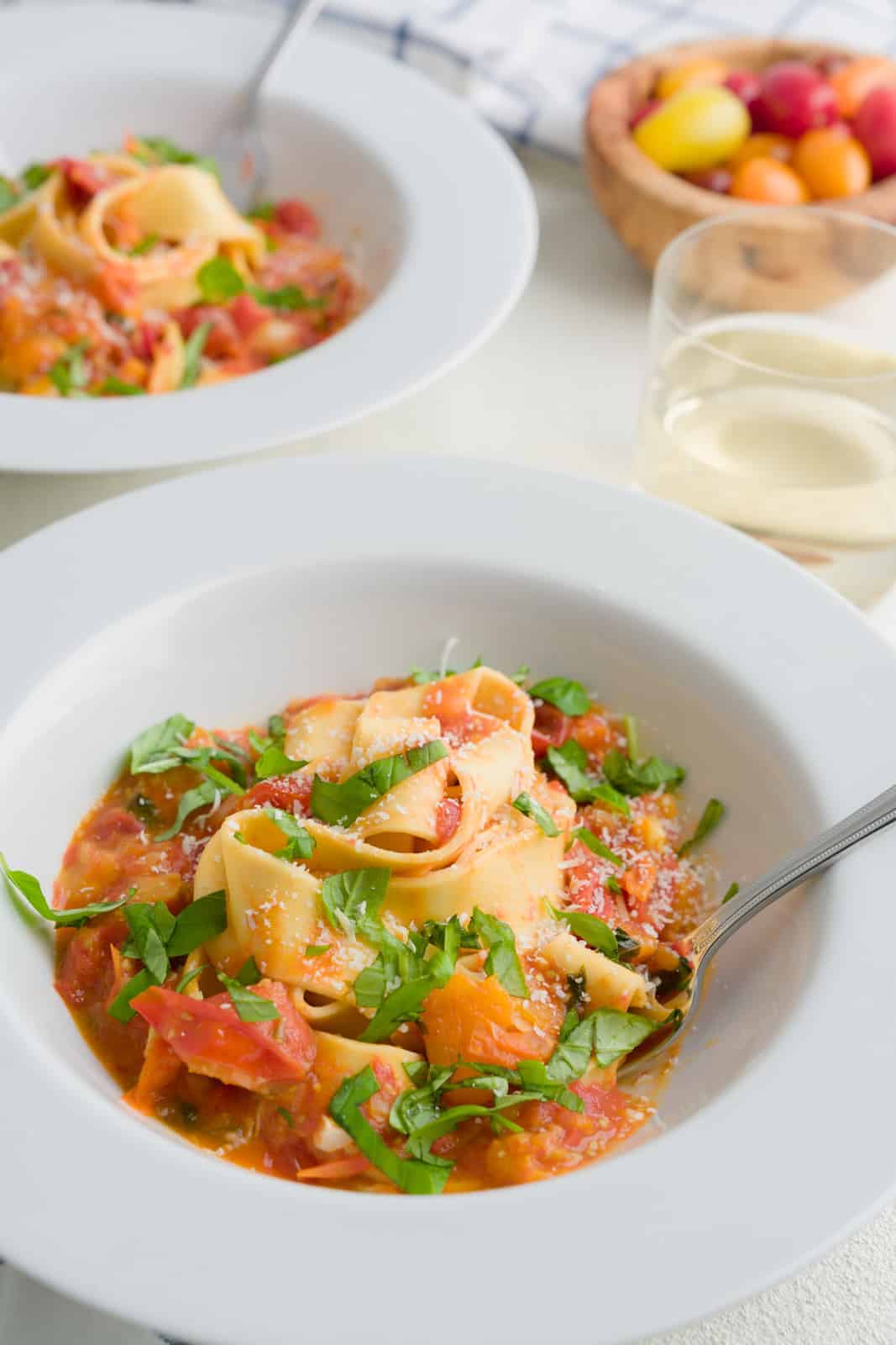 Served fresh tomato sauce on pasta - served in a white bowl next to a glass of white wine. 