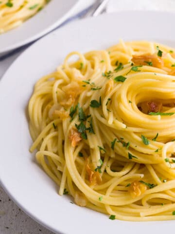 Simple garlic and olive oil pasta served in a plate garnished with parsley.