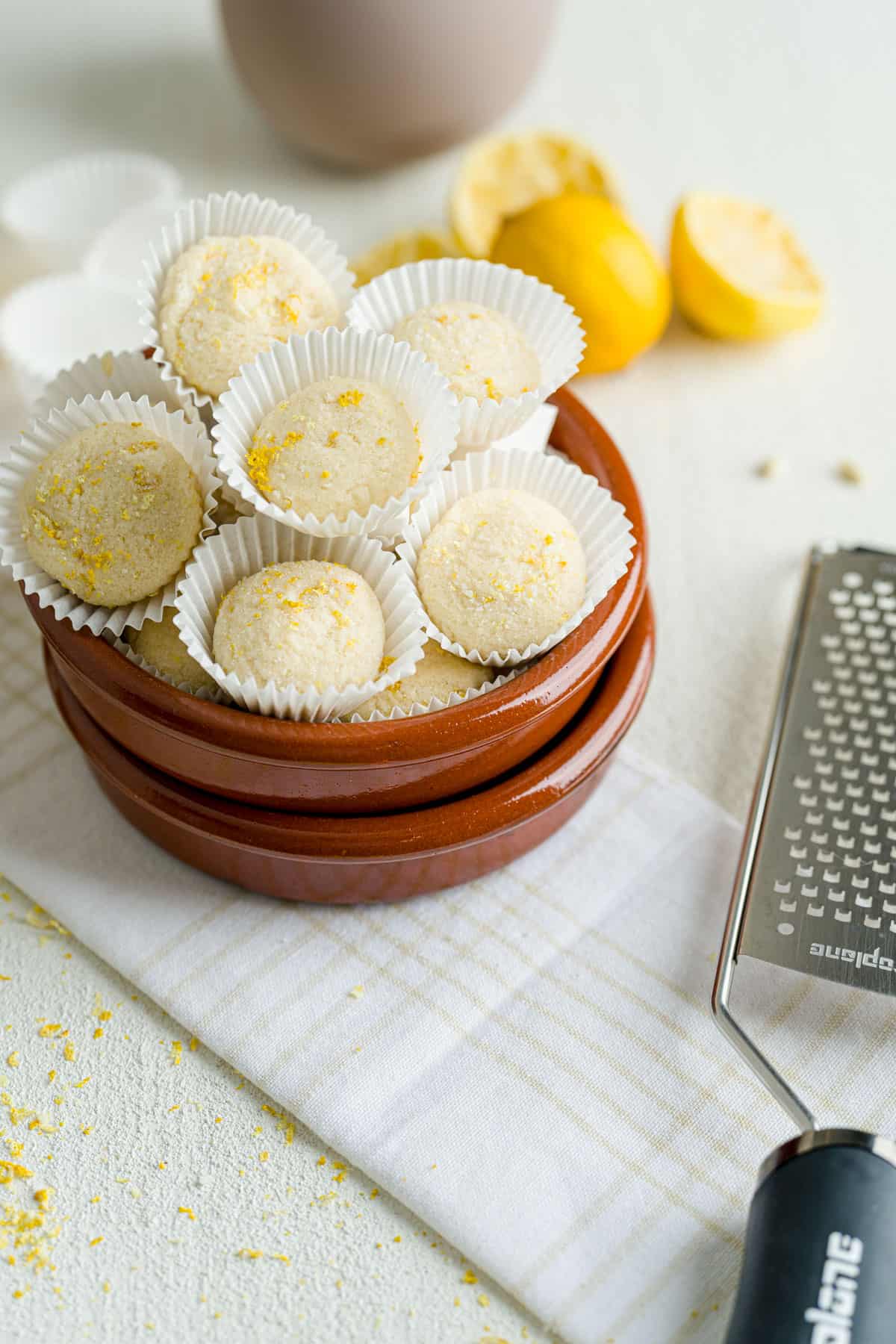 Stacked easy lemon truffles in mini baking cups next to a Microplane zester.