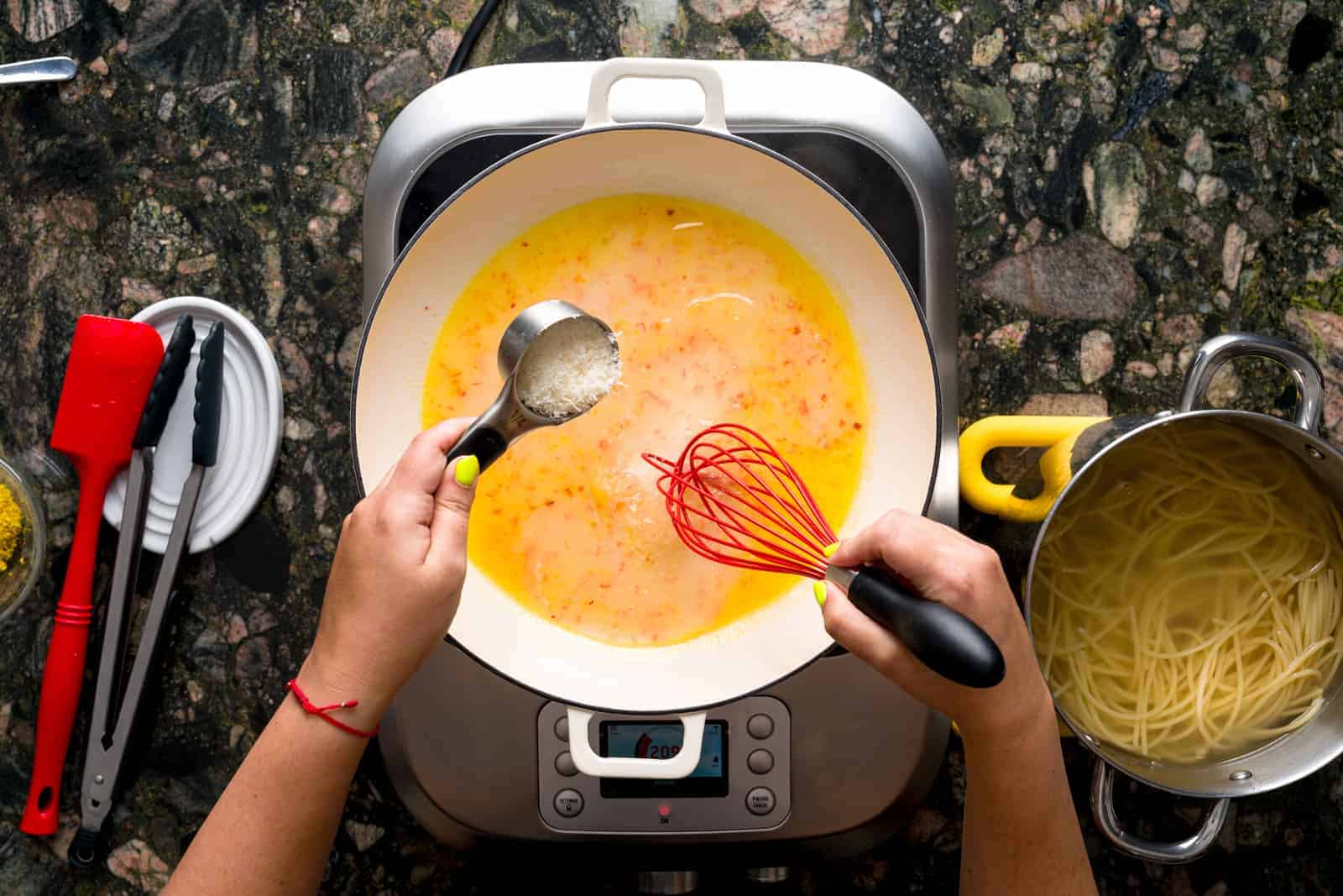Pasta al limone - pan showing sautéed shallots in olive oil and butter. Grated parmesan cheese is also being poured into the pan.