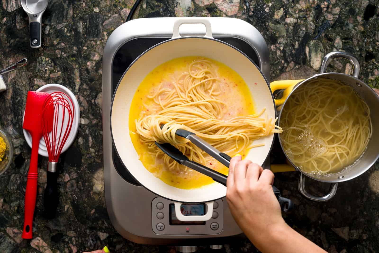 Pasta al limone - pasta being poured into pan with lemon sauce.