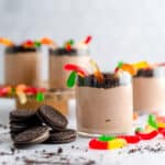 Set of four yogurt dirt cups with gummy worms and crushed Oreos.
