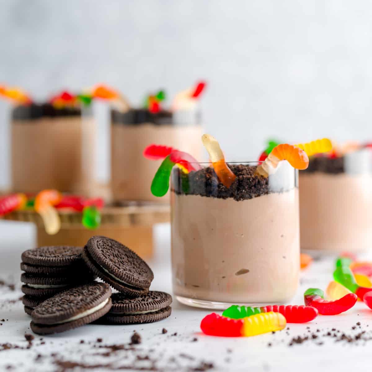 Nutella yogurt dirt cups layered with cookie crumbs and topped with gummy worms in clear glass cups.