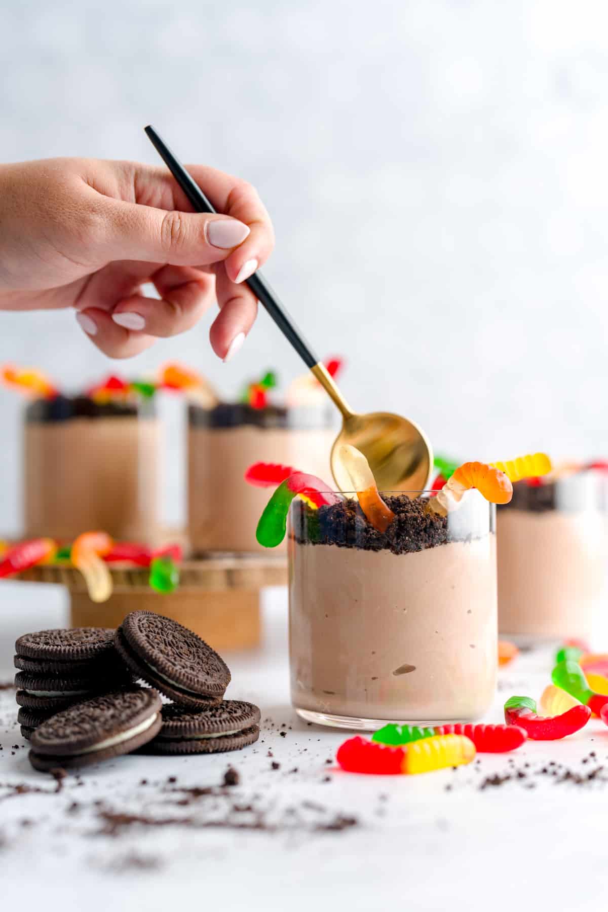Spoon about to dig into a Nutella yogurt dirt cups for kids Halloween with gummy worms and crushed Oreos.
