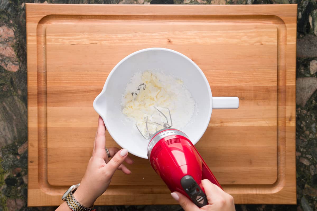 Combining mascarpone cheese, vanilla bean paste and powdered sugar with a handheld mixer for the mascarpone cream frosting.