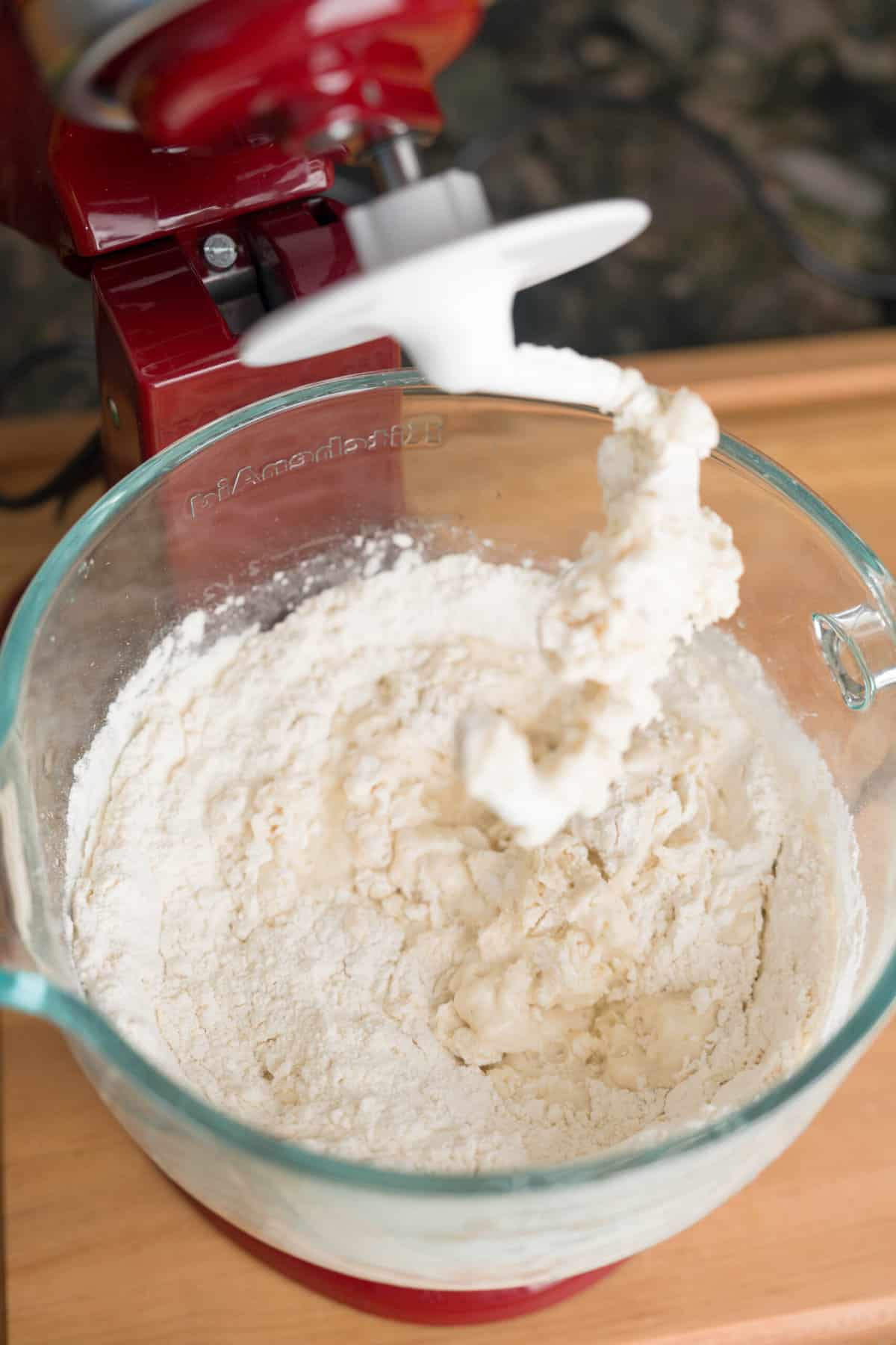 A stand mixer kneading sheet pan pizza dough.