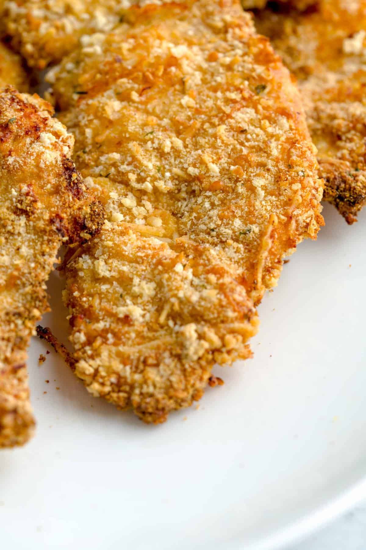 Close up shot of air fried chicken cutlets on a plate.
