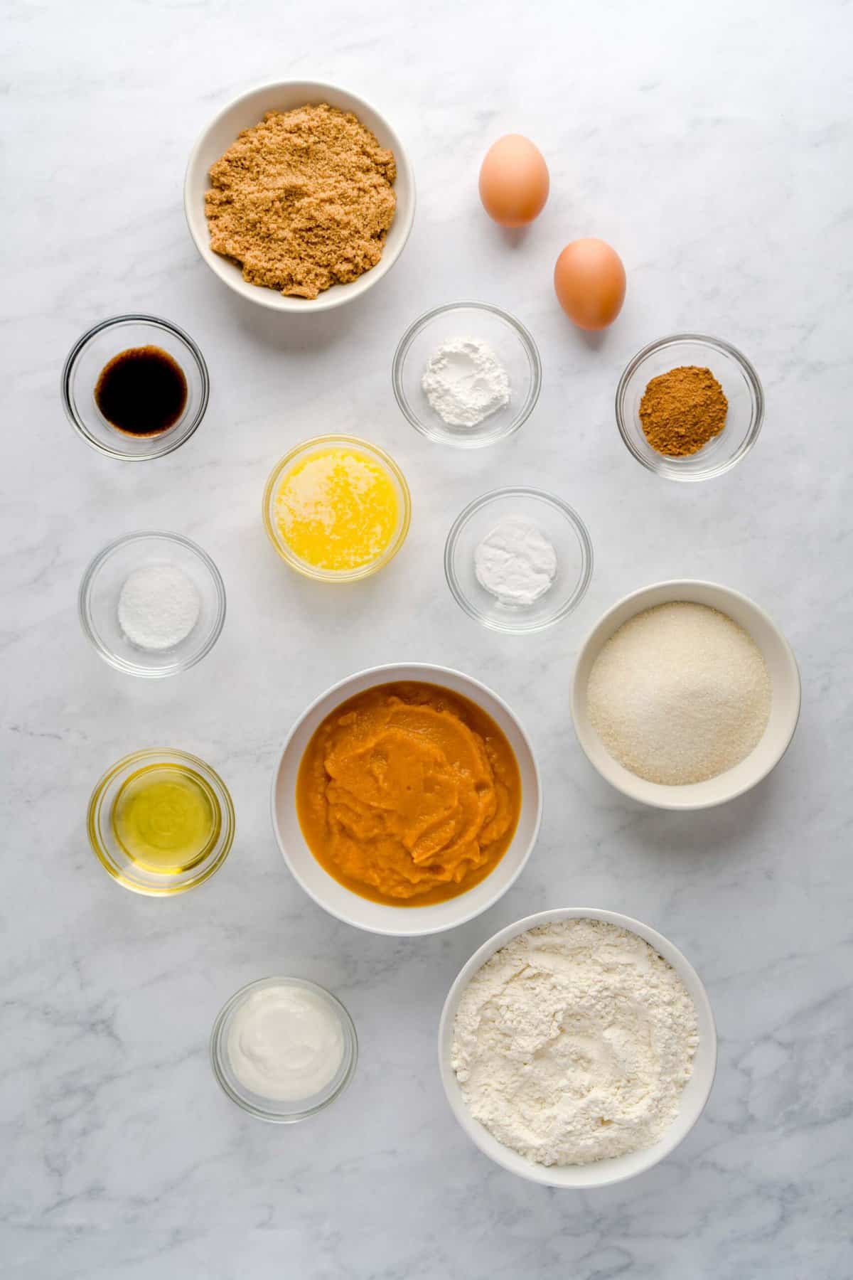 Ingredients needed to make pumpkin spice cake, including: brown sugar, eggs, ground pumpkin pie spice, baking soda, baking powder, granulated sugar, all-purpose flour, sour cream, pumpkin puree, avocado oil, kosher salt, melted butter and vanilla bean paste.