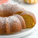 Pumpkin spice cake slice peeking out from the larger cake on a plate.