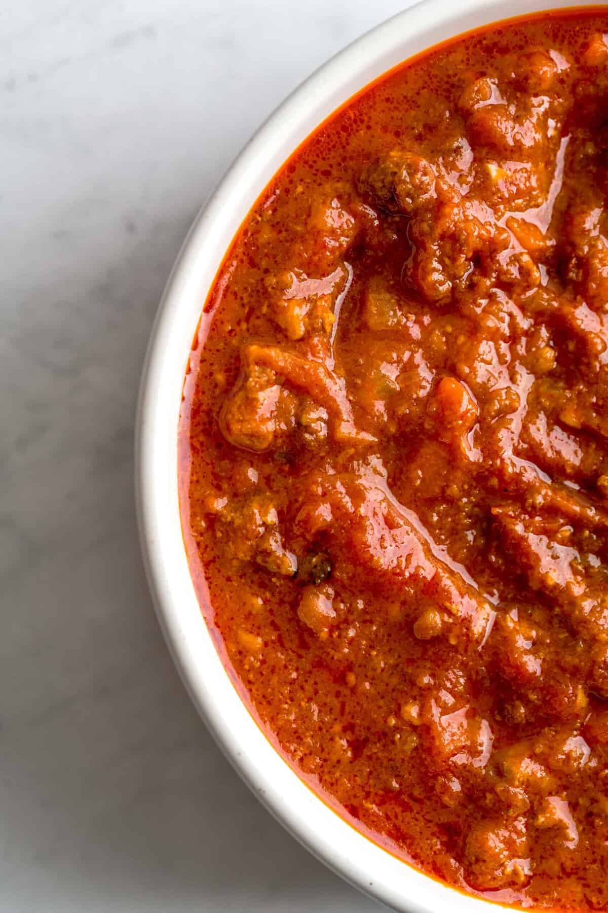 A close up shot of bolognese sauce in a white bowl.