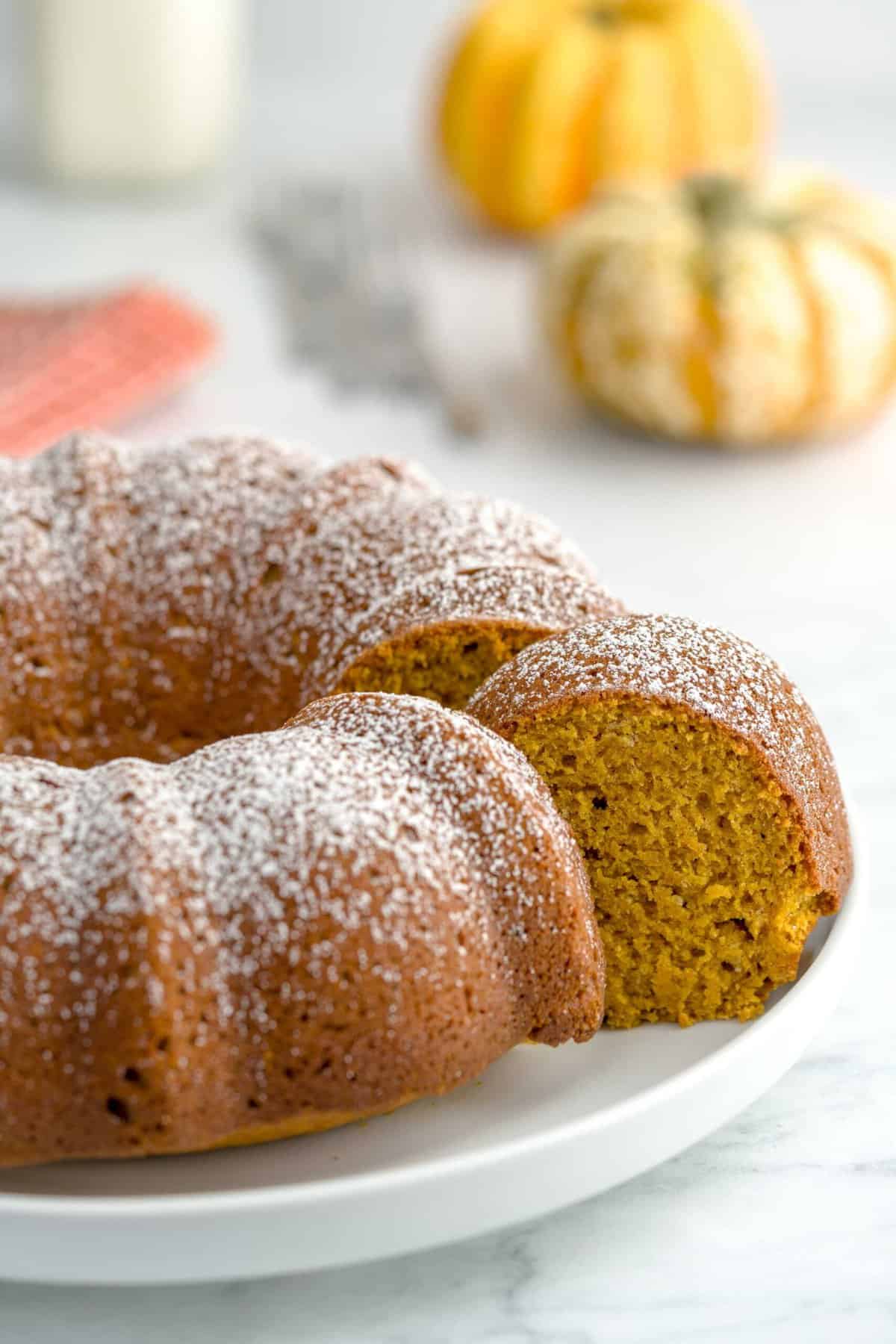 Pumpkin spice cake slice peeking out from the larger cake on a plate.