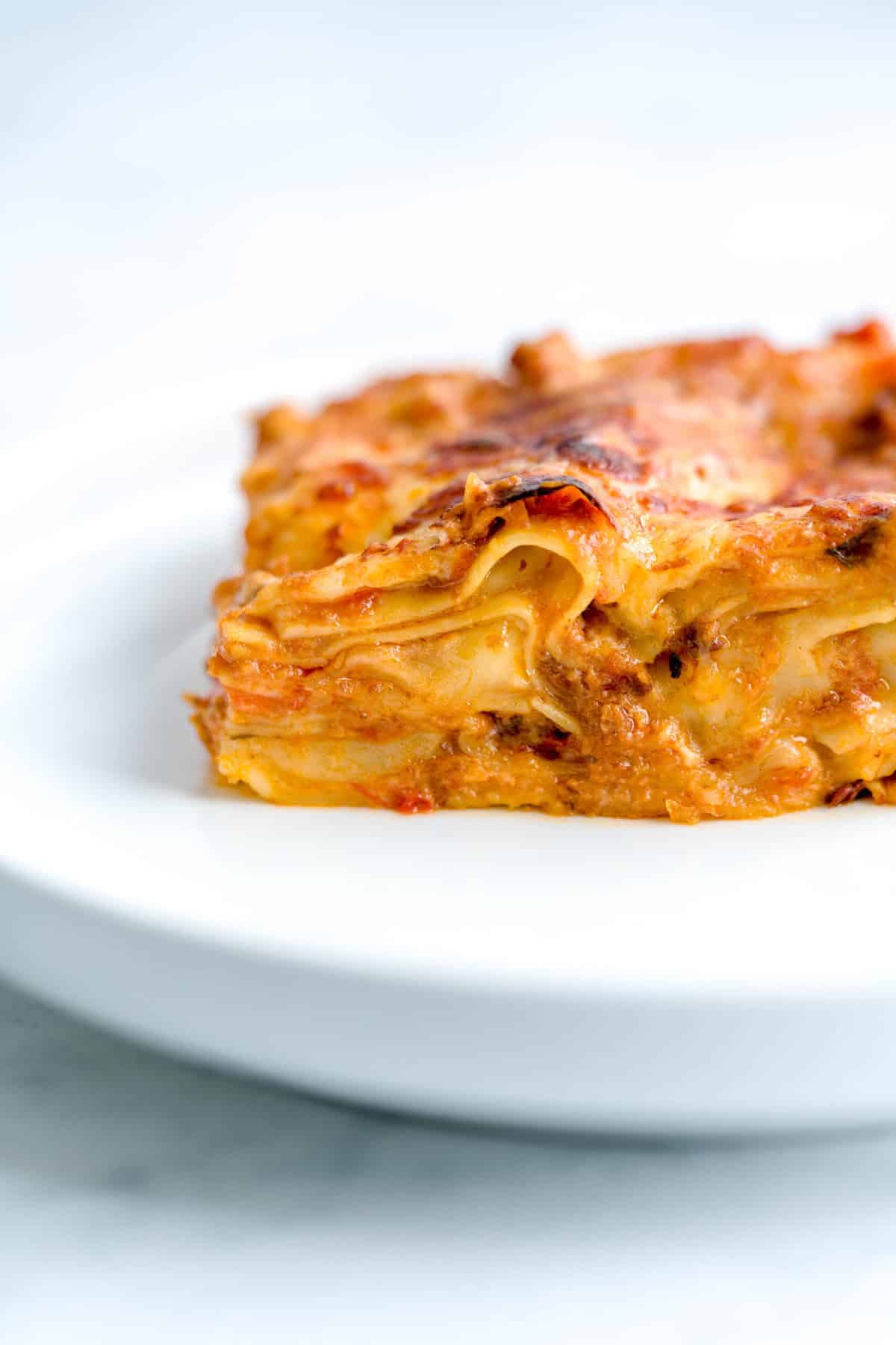Close up shot of a lasagna piece, showing layers of béchamel sauce, bolognese sauce and cheese.