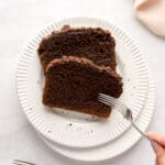 Two slices of chocolate espresso cinnamon loaf cake on a white plate while a fork digs in.