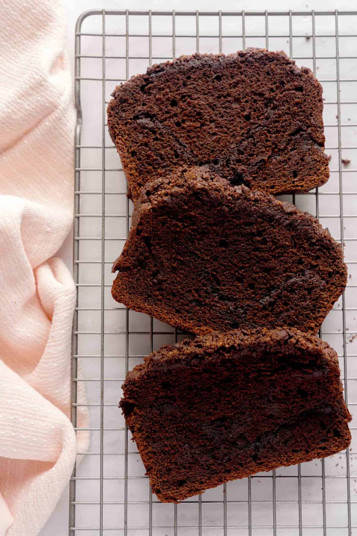 Overhead shot of chocolate espresso cinnamon loaf cake slices on a baking sheet next to a pink cloth napkin.