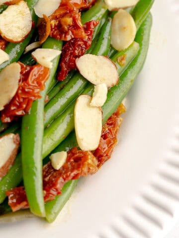 Zoomed shot of Italian green beans with sun-dried tomatoes and sliced almonds.