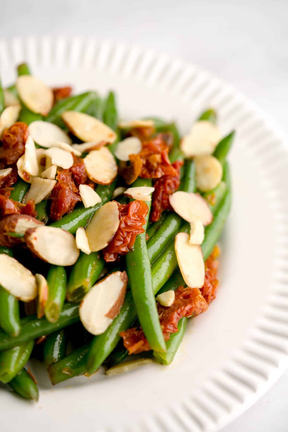 Zoomed shot of Italian green beans with sun-dried tomatoes and sliced almonds.