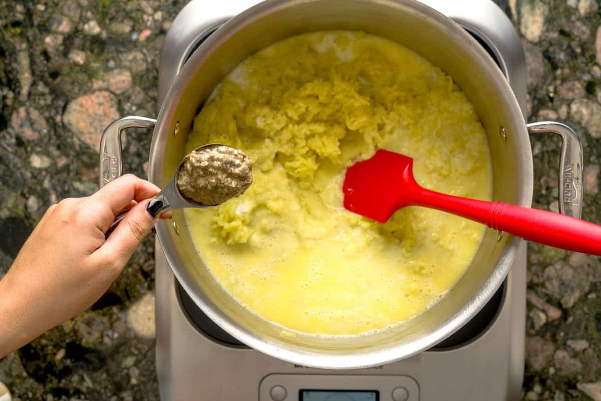 Overhead shot of truffle paste going into creamy mashed potatoes.