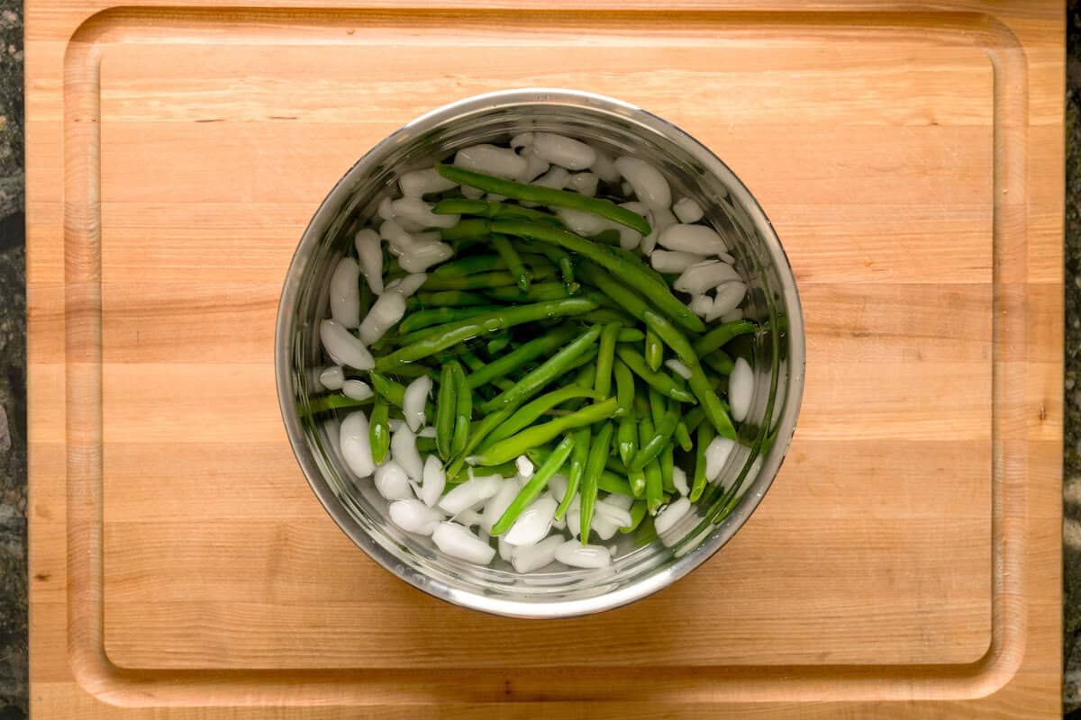 Overhead shot of green beans in an ice water bath.