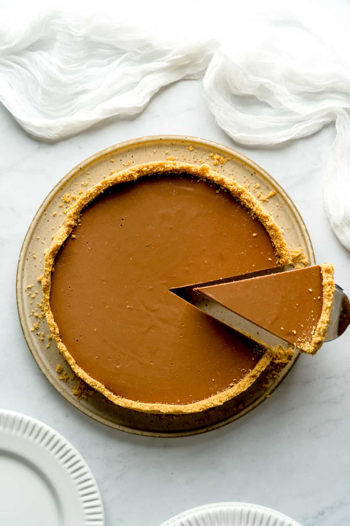 Overhead shot of slice of no bake Nutella cheesecake being served from larger pie.