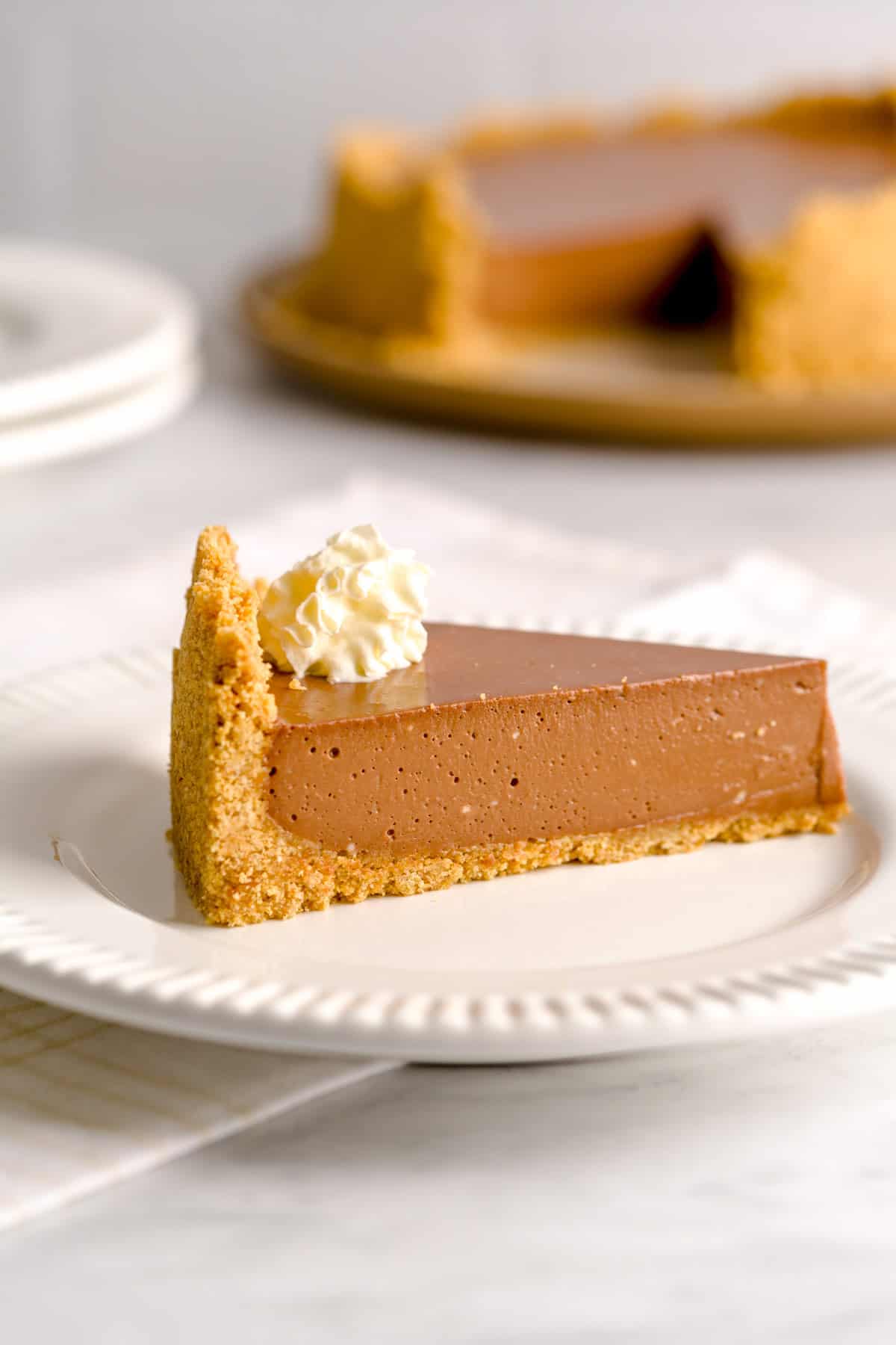 Slice of no bake Nutella greek yogurt cheesecake topped with whipped cream.