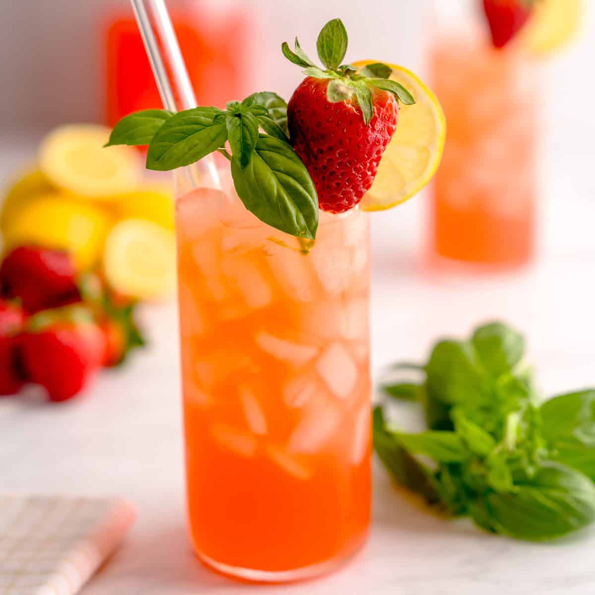 Iced strawberry basil lemonade garnished with a strawberry, lemon slice, and basil sprig.