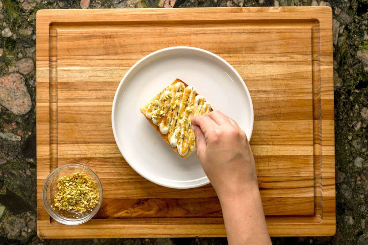Overhead shot of basil-lemon ricotta toast drizzled with pistachios.