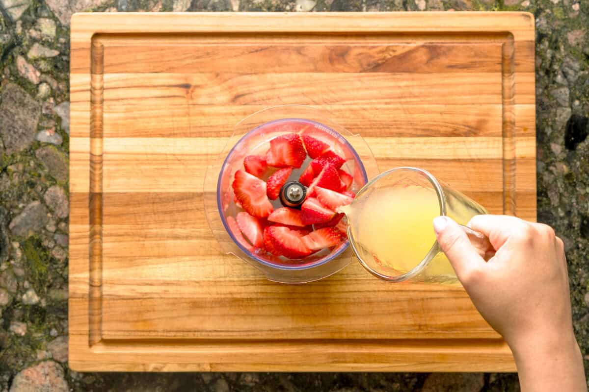 Overhead pour of fresh lemon juice into fresh strawberries.