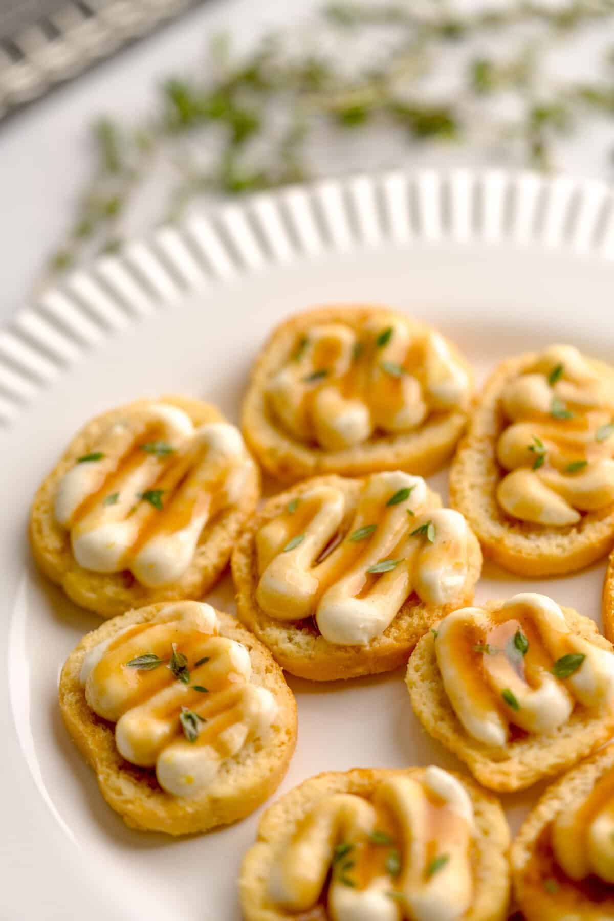 Close up shot of assembled crostini with whipped ricotta and truffle honey, garnished with fresh thyme.