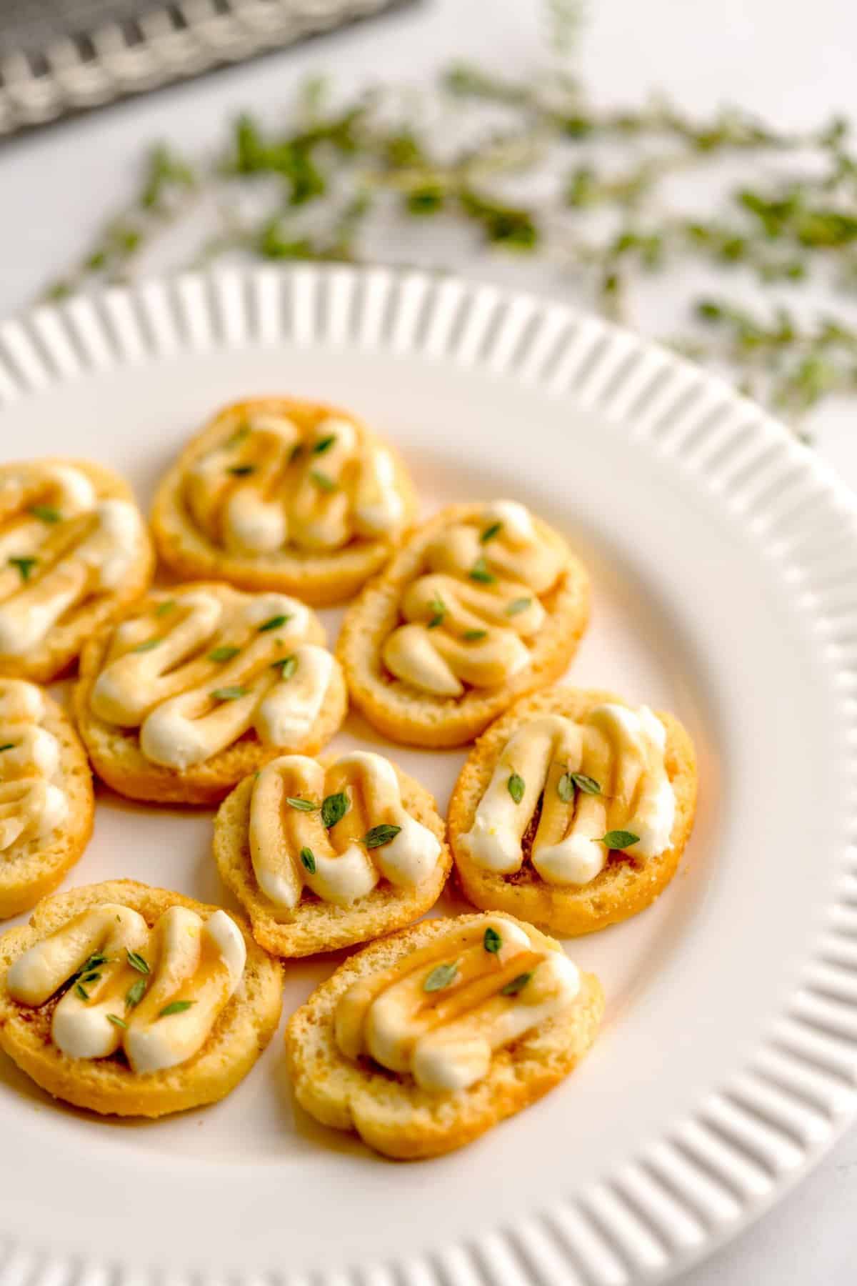 Close up shot of assembled crostini with whipped ricotta and truffle honey, garnished with fresh thyme.