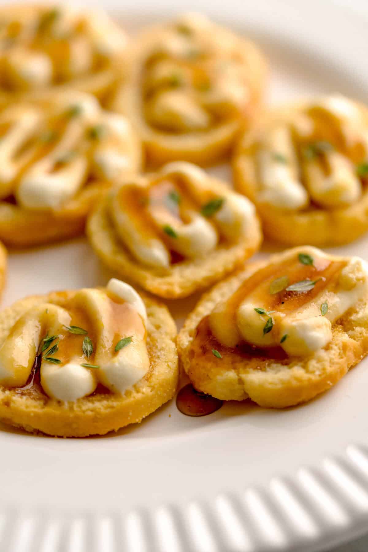 Close up shot of assembled crostini with whipped ricotta and truffle honey, garnished with fresh thyme.