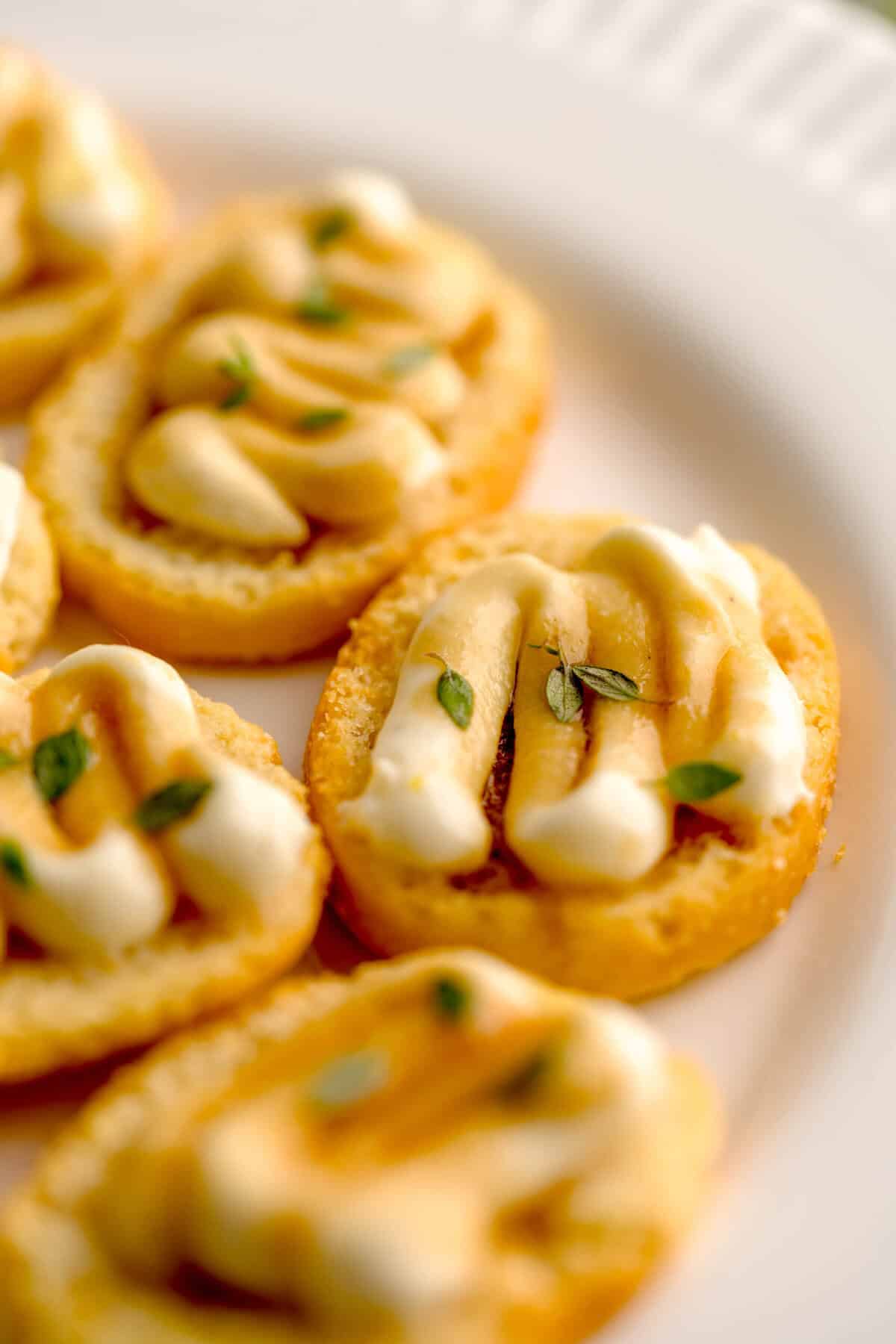 Close up shot of assembled crostini with whipped ricotta and truffle honey, garnished with fresh thyme.