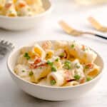 Bowl served with easy creamy pasta with parmesan, peas and prosciutto.
