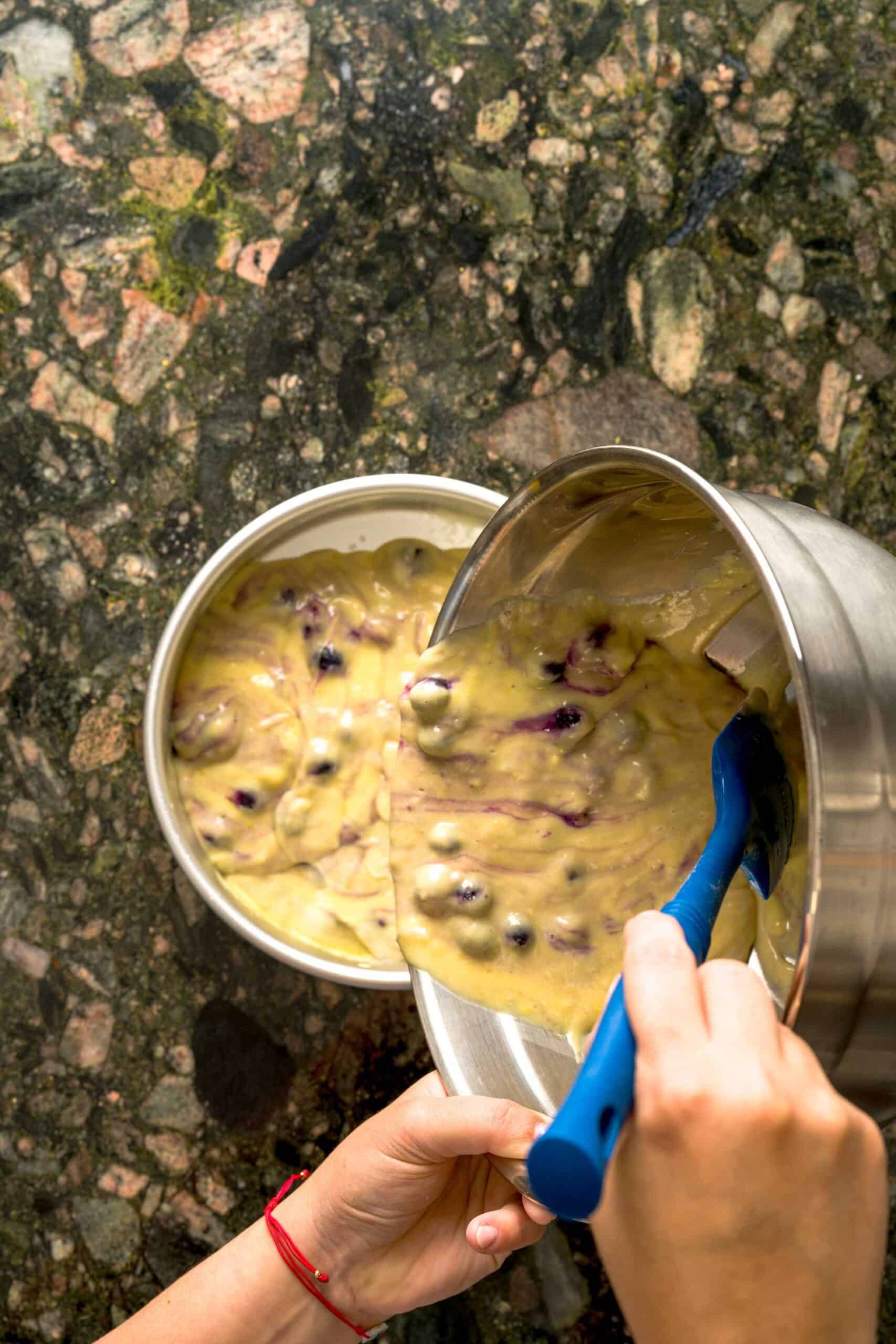 Pouring moist lemon blueberry cake batter into cake pan.