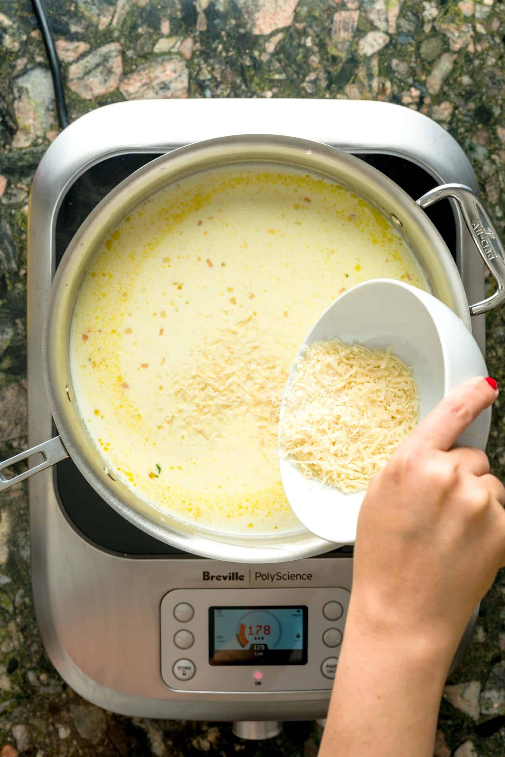 Adding parmesan cheese to creamy pasta al limone sauce.