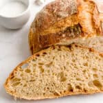 A slice of homemade Italian bread in front of a half loaf.