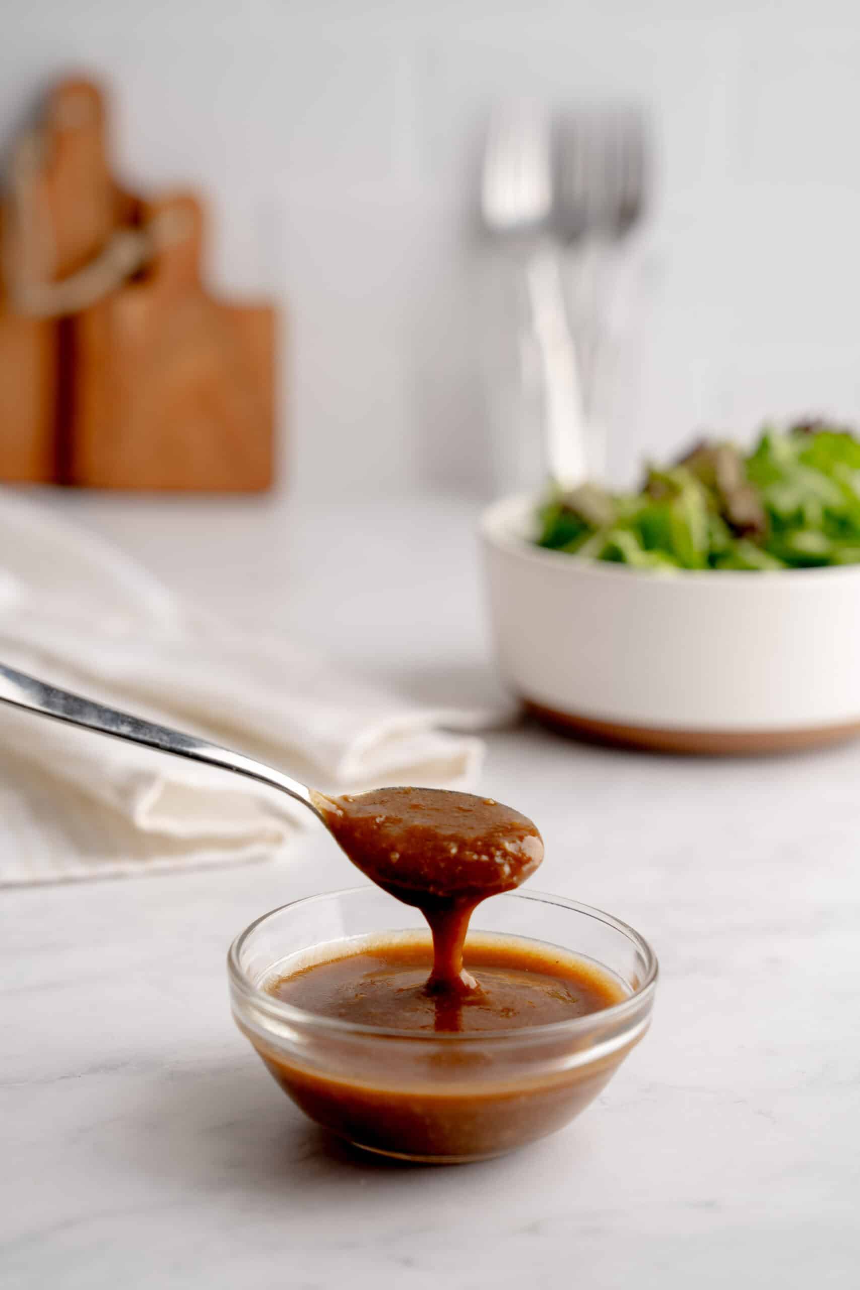Creamy balsamic vinaigrette with roasted garlic in front of a fresh salad.