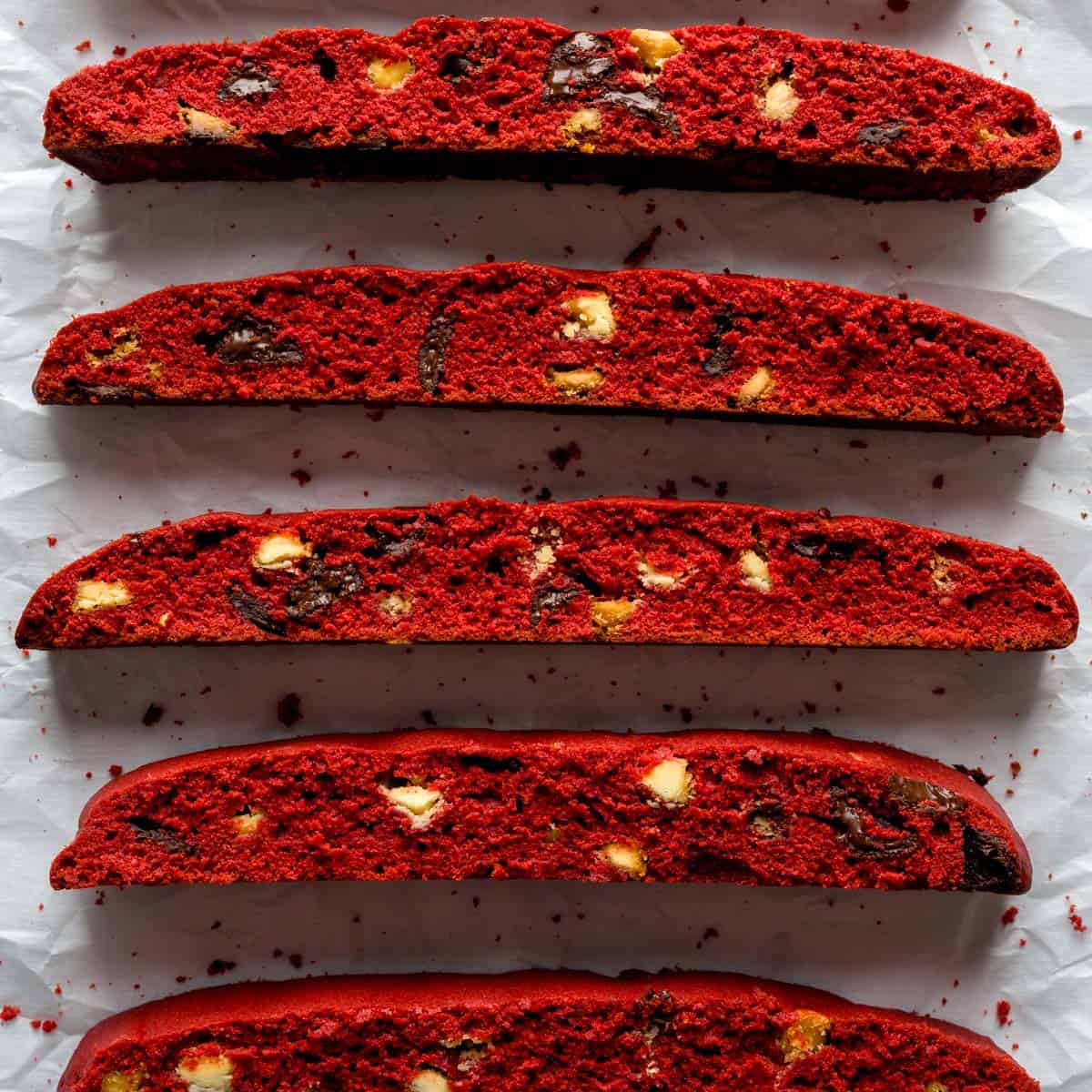 Five slices of red velvet biscotti on parchment paper