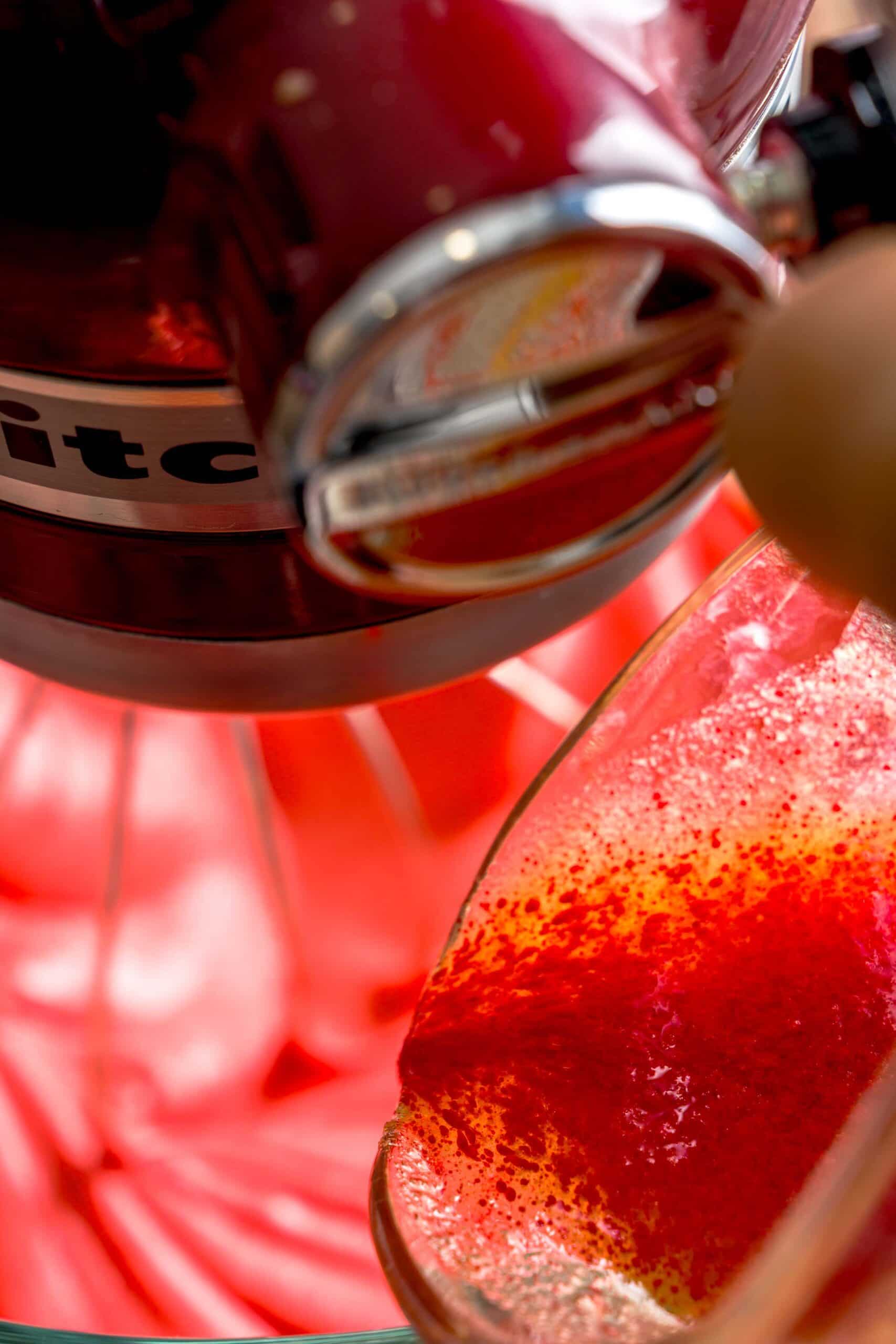 Red food coloring and butter being poured into stand mixer for Italian red velvet biscotti