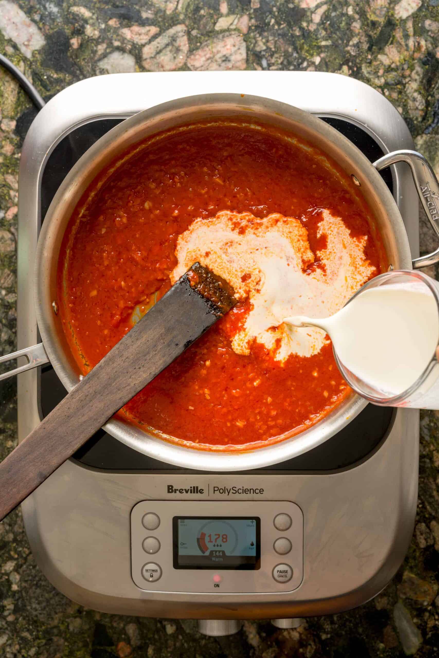 Heavy cream poured into pan to make creamy vodka sauce.