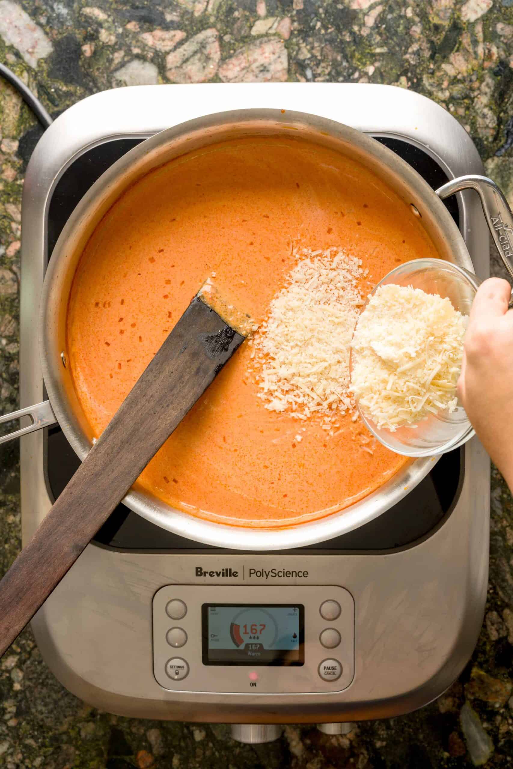 Sprinkling parmesan cheese into pan to make creamy vodka pasta sauce recipe.