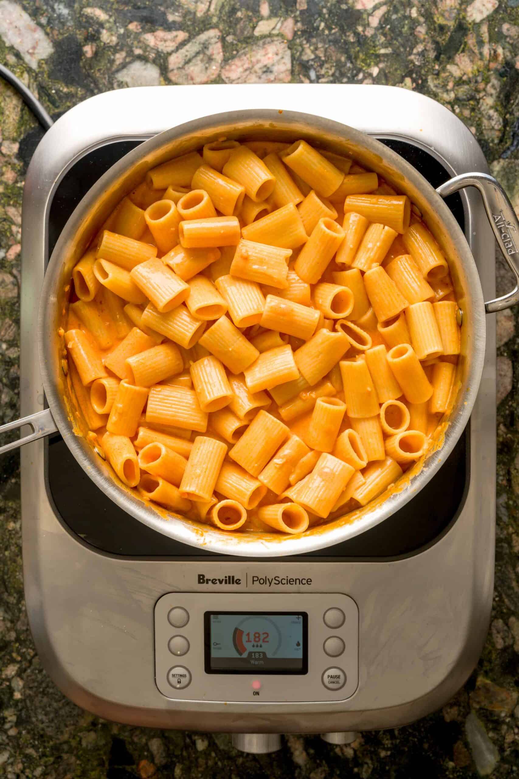 Marrying pasta with creamy vodka sauce in large pan over burner.