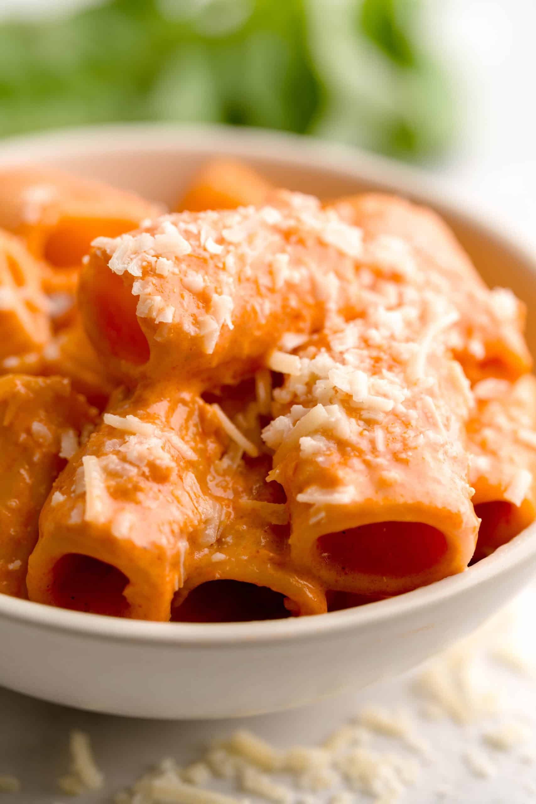 A bowl of vodka pasta sprinkled with grated parmesan cheese.