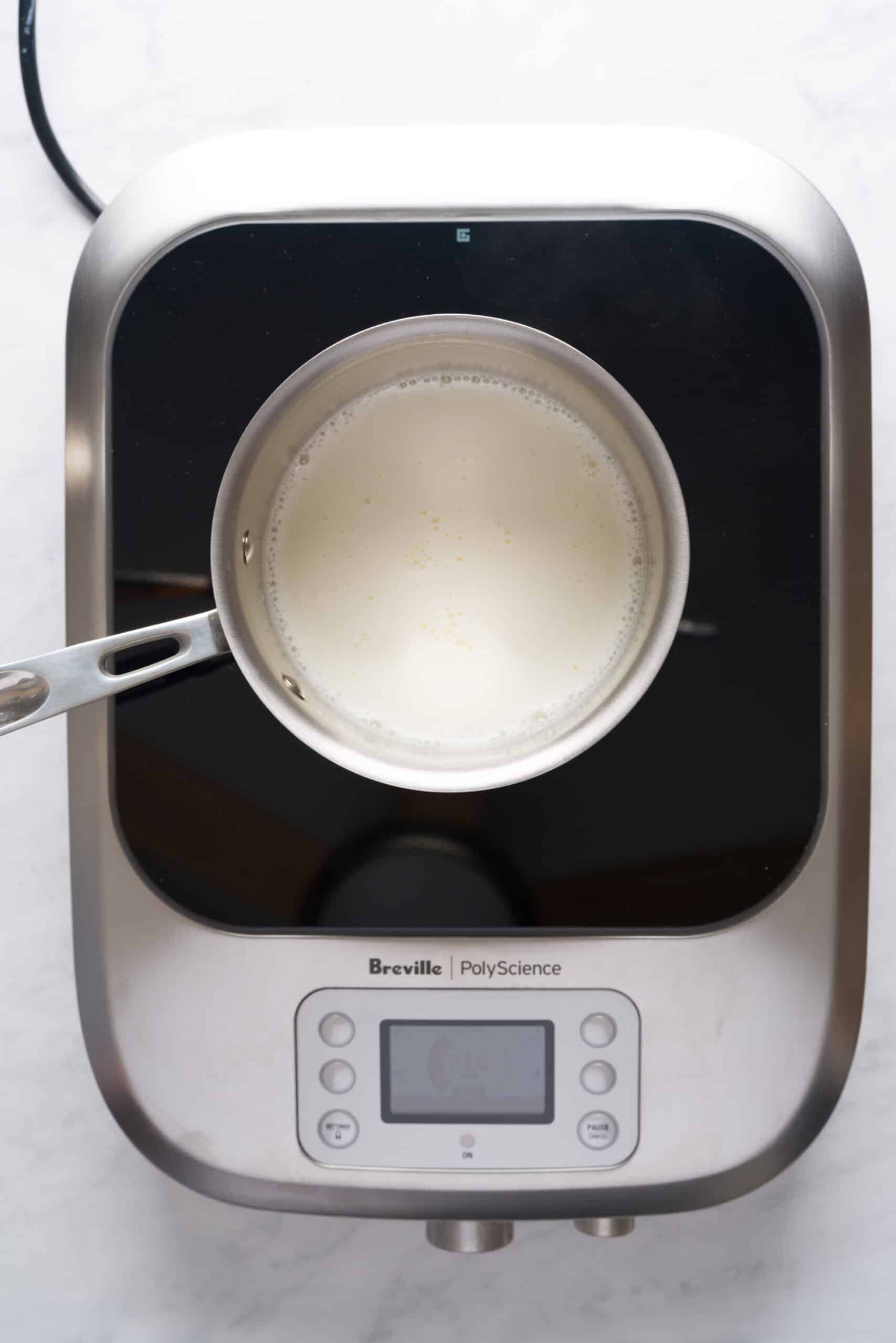 Milk and cream being steamed in a pot over a burner.