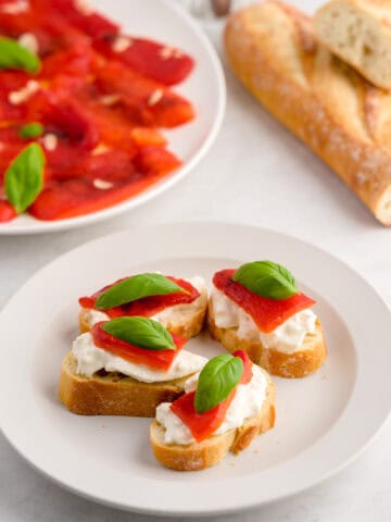 Delicious Italian roasted red peppers with basil on toasted baguette slices.