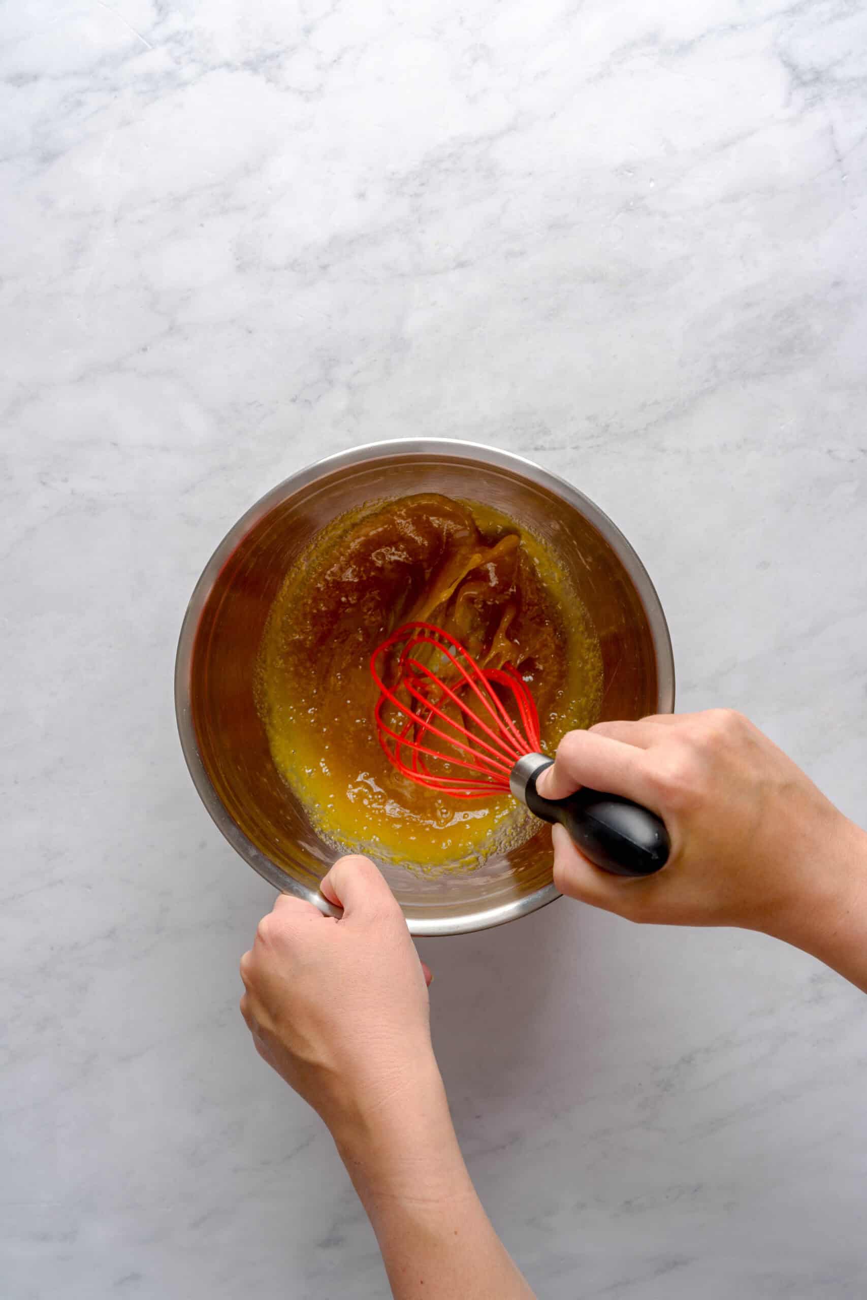 Whisking eggs and maple syrup in a bowl to make pumpkin spice gelato custard base.